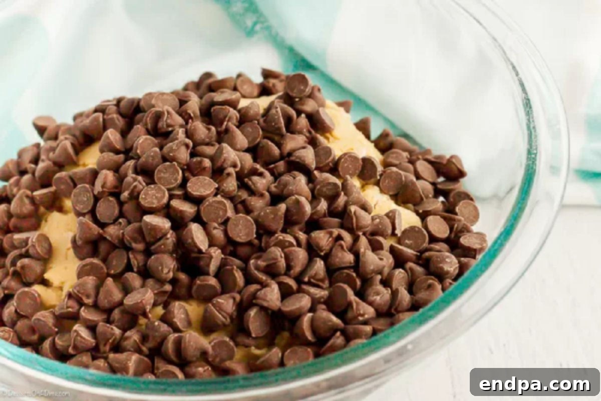 The chocolate chip cookie cake dough, thick and rich, with an abundance of chocolate chips mixed throughout, ready for baking.