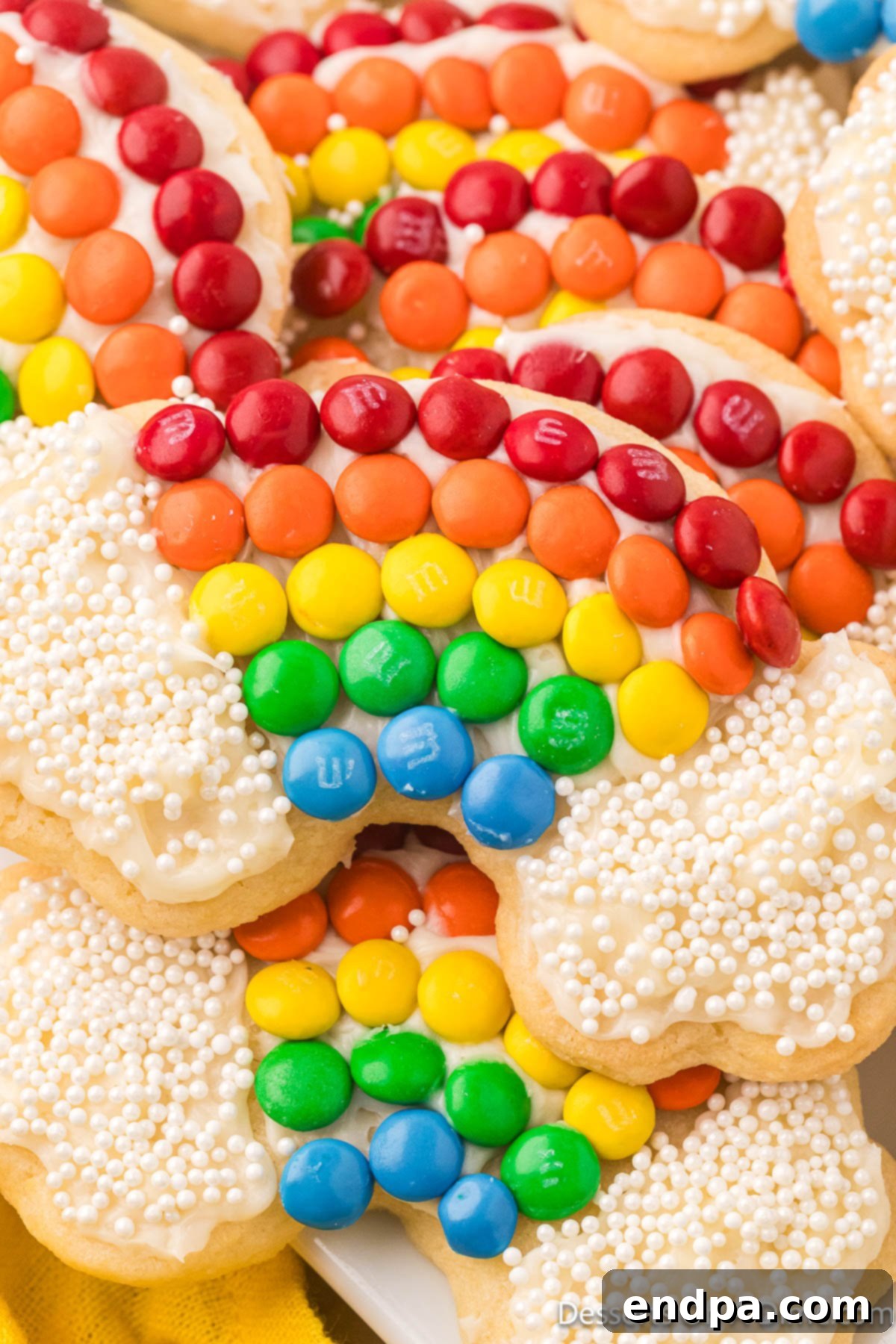 Vibrantly decorated Rainbow Cookies featuring a cheerful arc of M&M candies and white sprinkles, arranged on a baking sheet, ready to bring joy to any occasion.