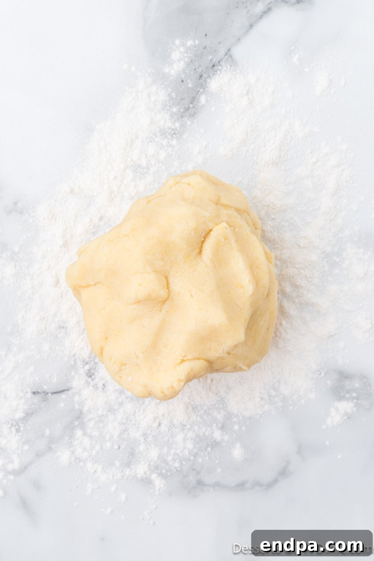 A ball of freshly prepared sugar cookie dough, ready to be rolled out on a floured surface.