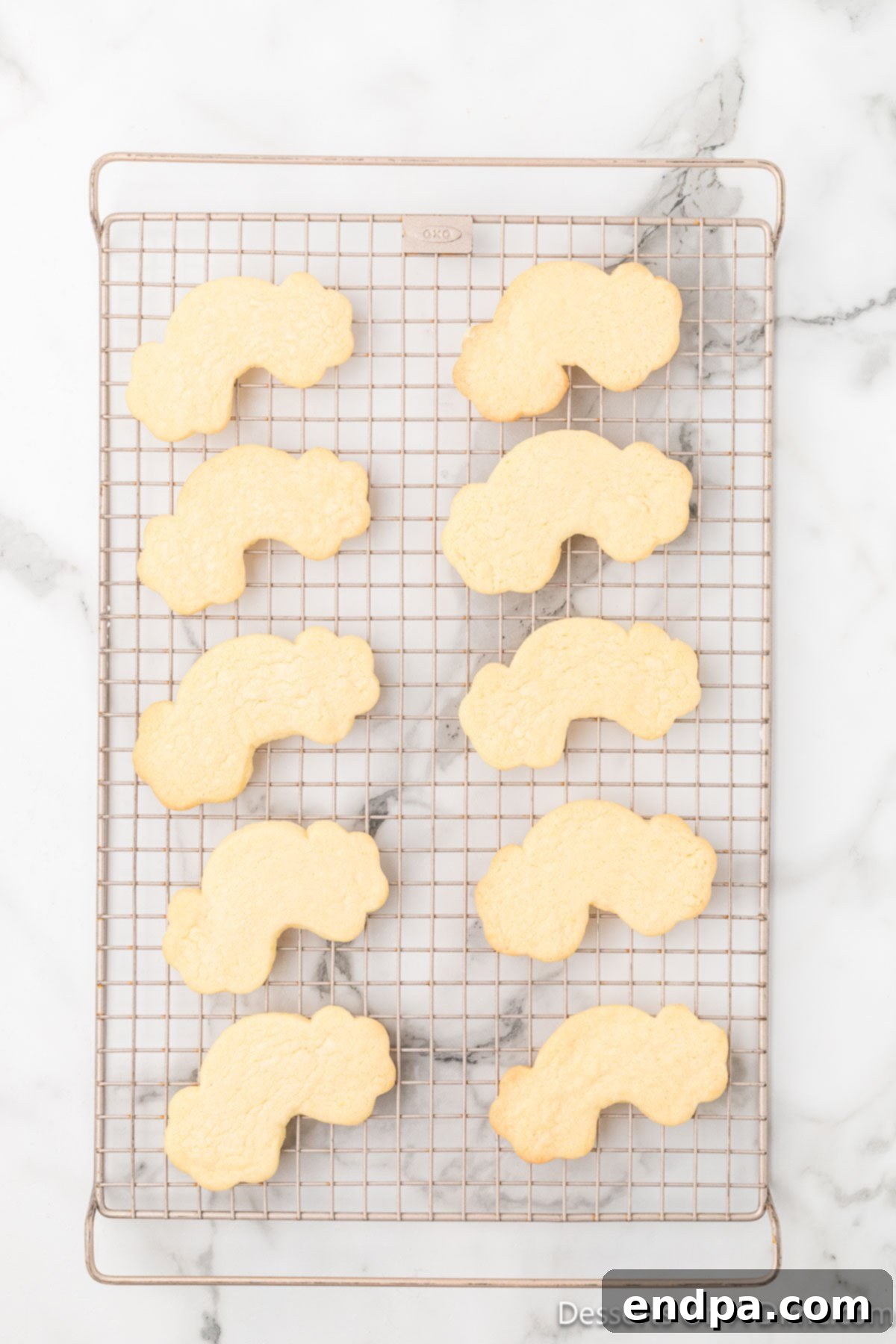 Freshly baked rainbow cookies cooling on a wire rack after being removed from the oven.
