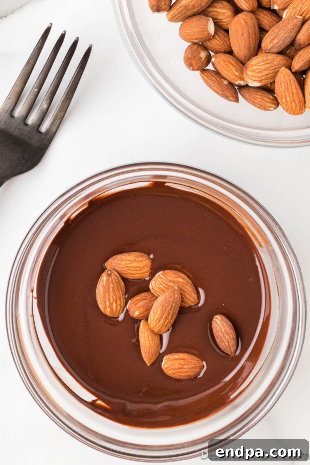 Decadent Dark Chocolate Almonds 5 Raw almonds being gently stirred into a bowl of rich melted dark chocolate for coating.
