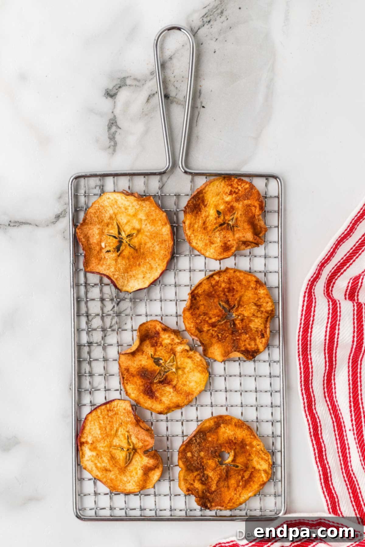 Sweet & Crispy Air Fryer Apple Chips 11 Golden, crispy apple slices cooling on a wire rack, allowing for optimal air circulation.