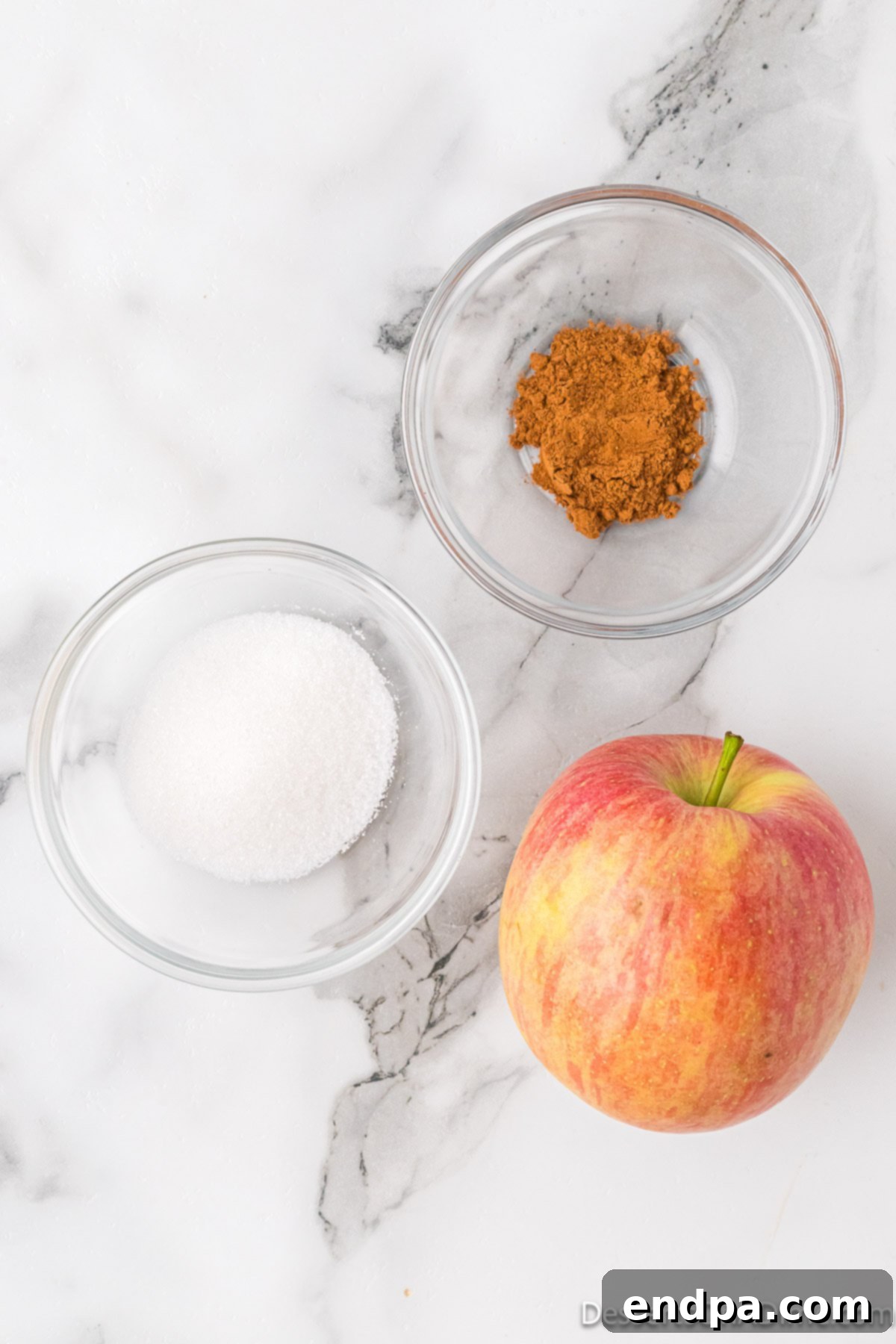 Sweet & Crispy Air Fryer Apple Chips 3 Key ingredients for Air Fryer Apple Chips, including fresh apples, granulated sugar, and ground cinnamon, neatly arranged.