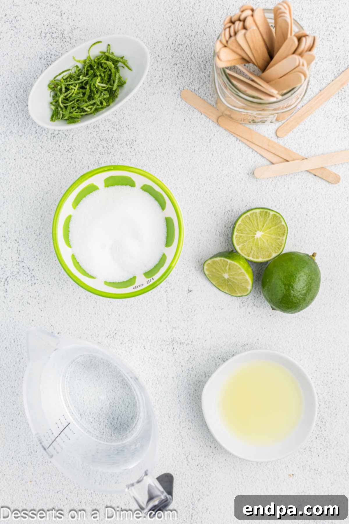 Fresh limes and other ingredients laid out for making homemade lime popsicles.