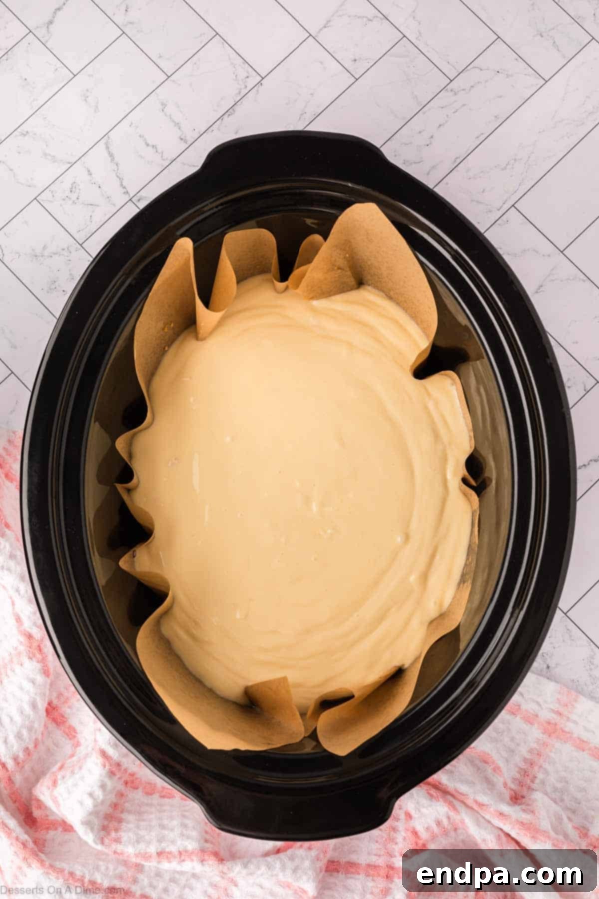 Slow Cooker Cheesecake 9 Cheesecake poured into crock pot on top of crust