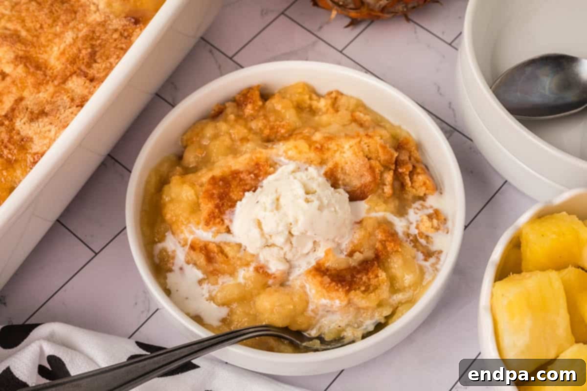 Pineapple dump cake in a bowl topped with ice cream. 