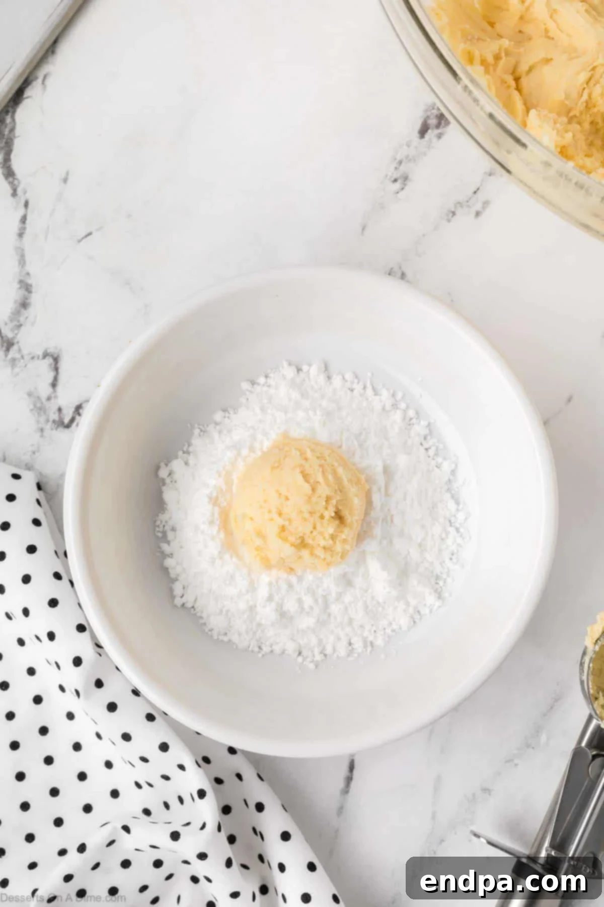 Cake Mix Butter Cookies: Ooey Gooey Goodness 8 Dough balls dropped into powdered sugar in a bowl.