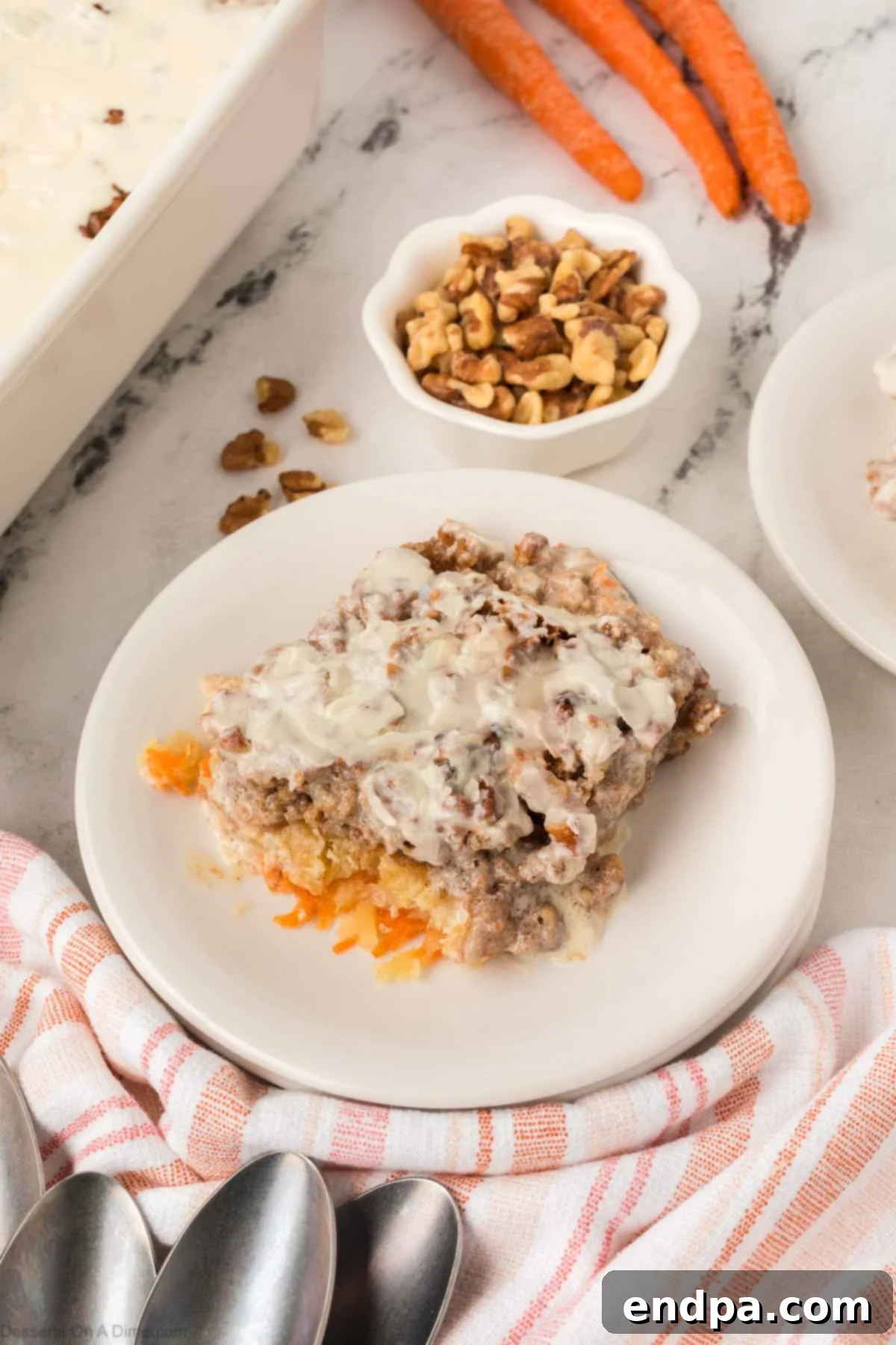 A white plate showcasing a delectable slice of Carrot Cake Dump Cake, topped with creamy frosting.